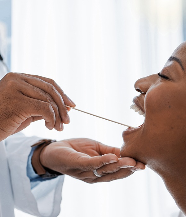 a dentist swabbing a patient’s mouth