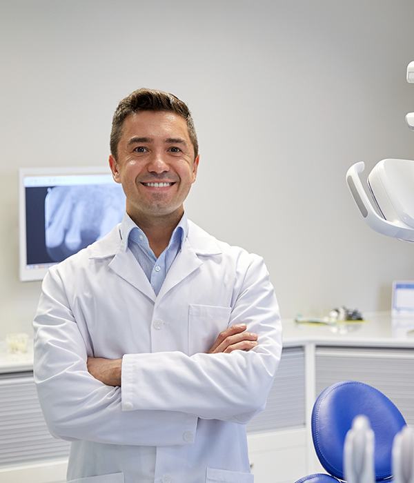 a dentist standing in an operatory with his arms crossed